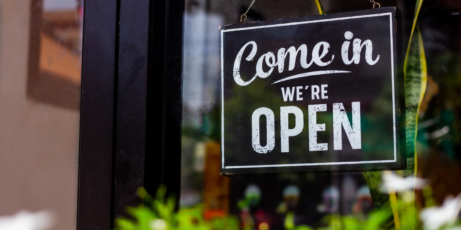 A Come in, we’re open sign hanging in a shop window